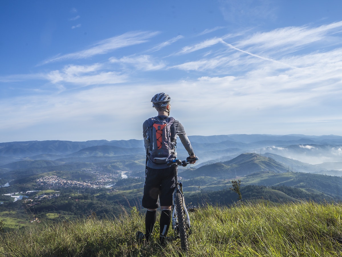 Image of a man standing on grass with his bike